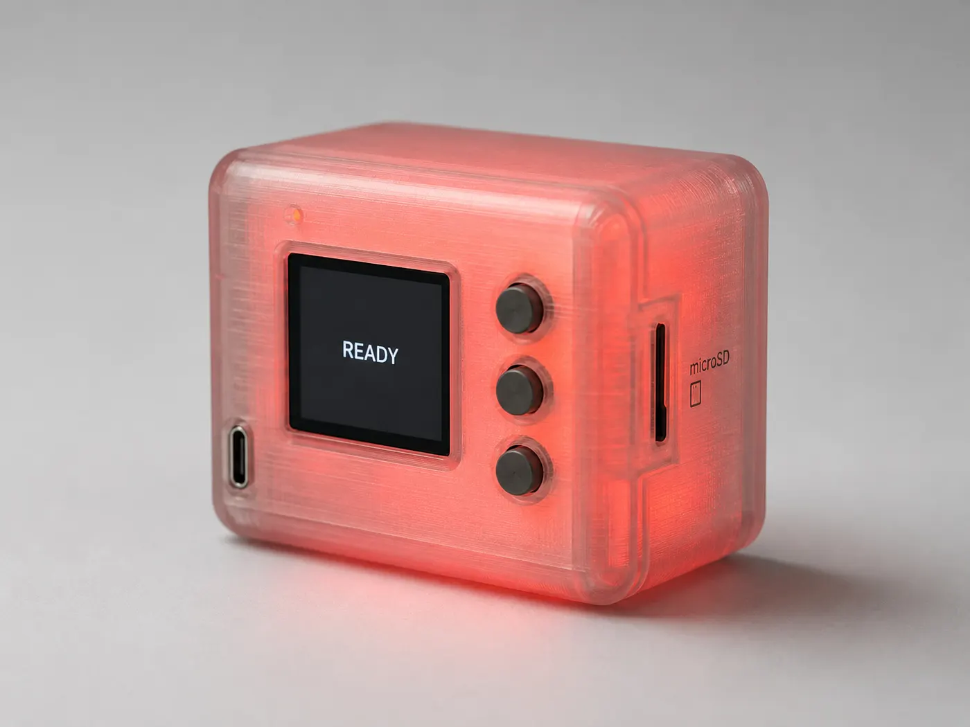 Early translucent-shell concept render of the Darkroom: a frosted enclosure glowing red from within, a small screen reading READY, three buttons, USB-C, and a microSD slot.
